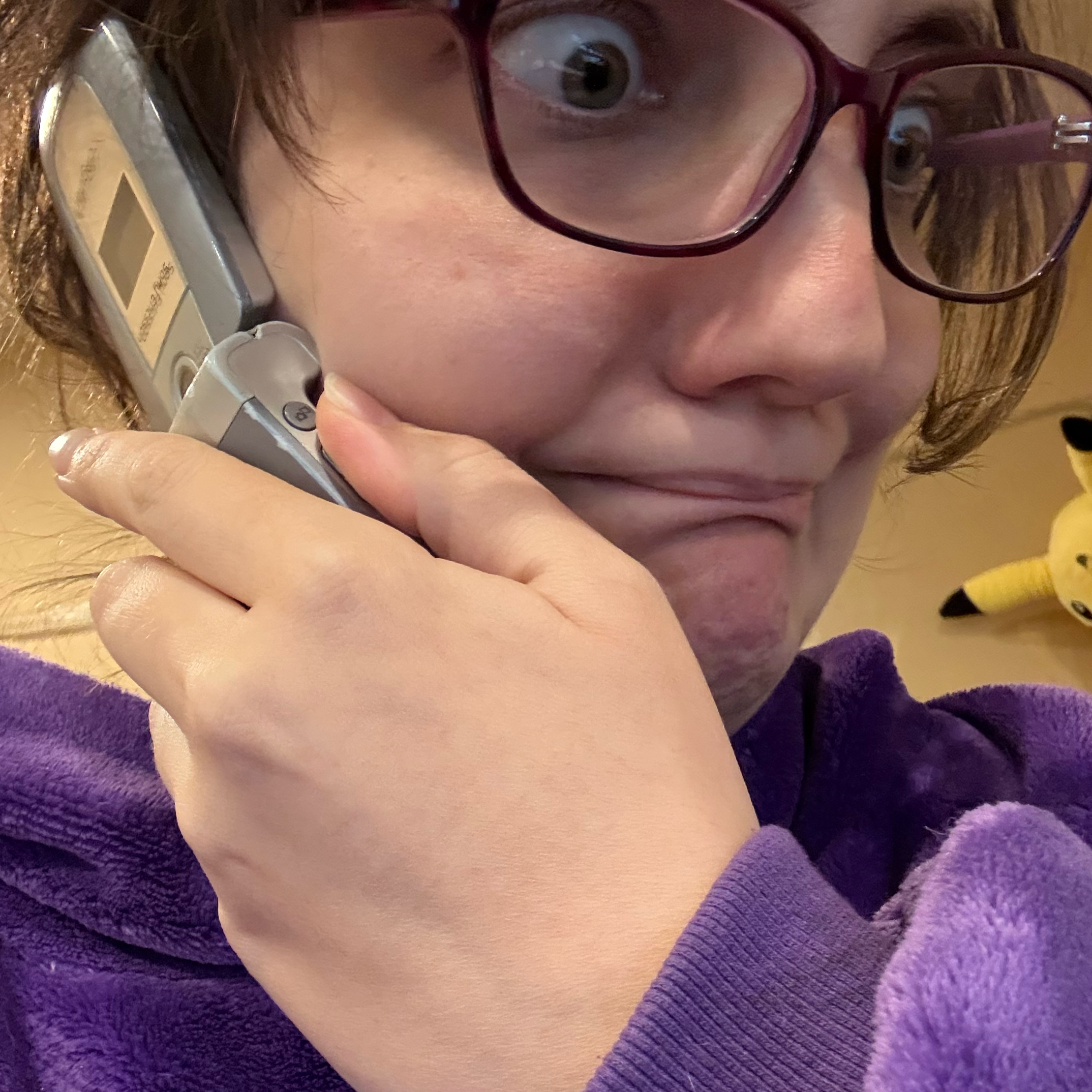 female-shaped creature stares in panic, holding an old cell phone to their ear